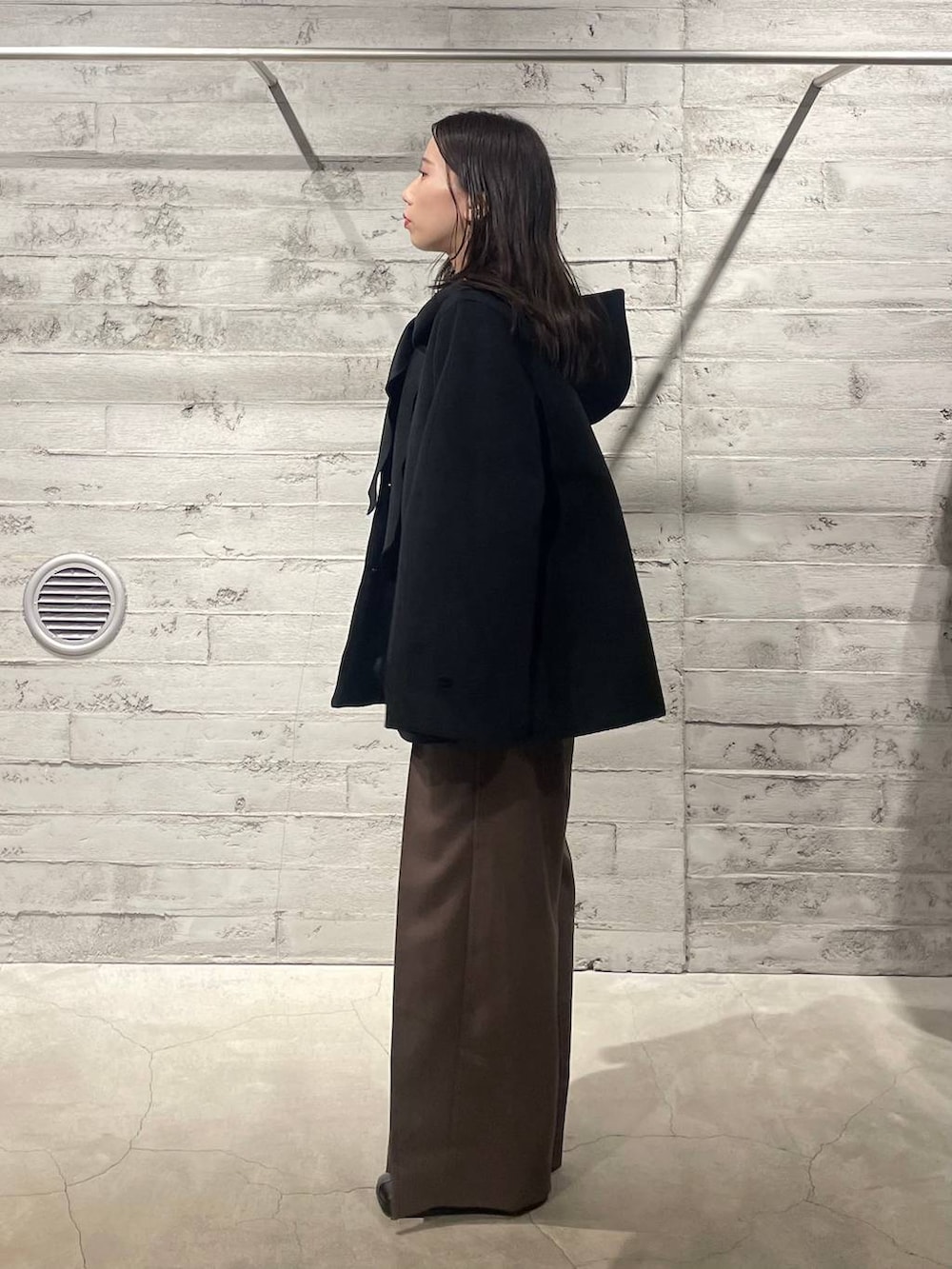 ブラック系のブーツ、ブラック系のノーカラーコート、ブラウン系のその他パンツを着用したレディースの冬コーディネートの2枚目の写真