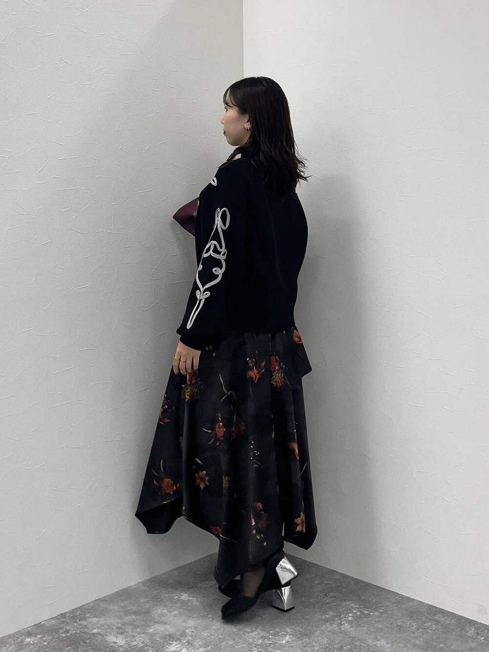 レッド系のトートバッグ、ブラック系のブーツ、ブラック系のニット/セーターを着用したレディースの夏コーディネートの2枚目の写真