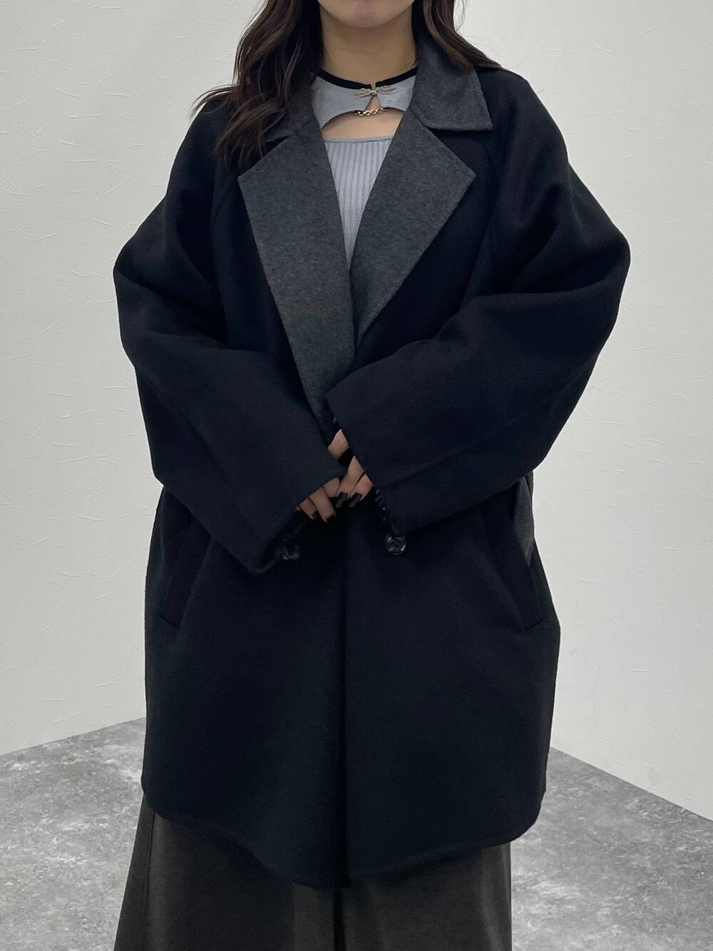 グレー系のニット/セーター、ブラック系のチェスターコート、ブラック系のブーツを着用したレディースの秋コーディネートの6枚目の写真