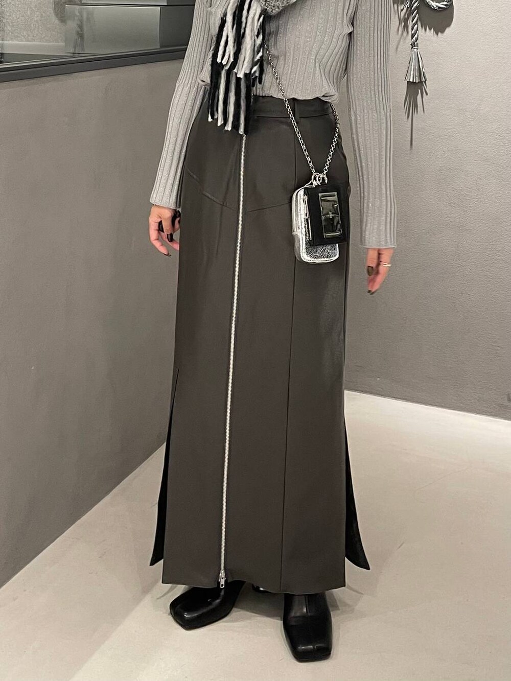 ホワイト系のニット/セーター、ブラック系のブーツ、グレー系のスカートを着用したレディースの冬コーディネートの6枚目の写真