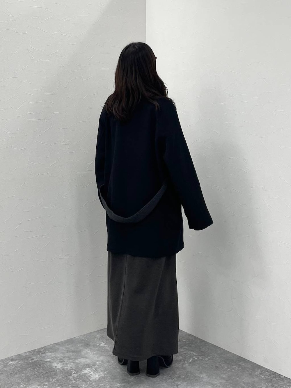 グレー系のニット/セーター、ブラック系のチェスターコート、ブラック系のブーツを着用したレディースの秋コーディネートの4枚目の写真