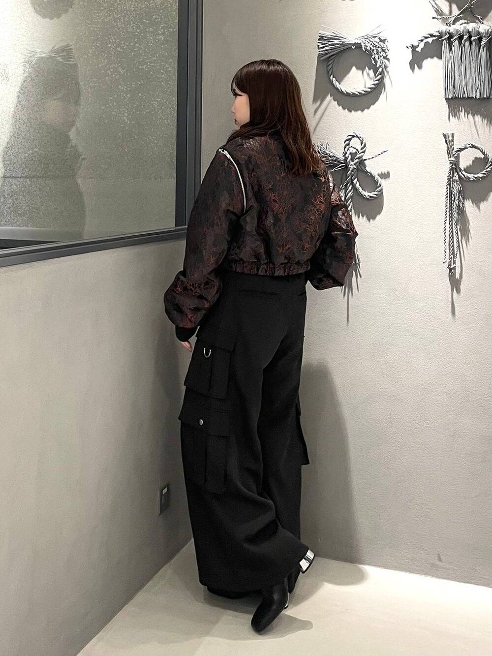 オレンジ系のブルゾン、ブラック系のブーツ、ブラック系のニット/セーターを着用したレディースの秋コーディネートの2枚目の写真