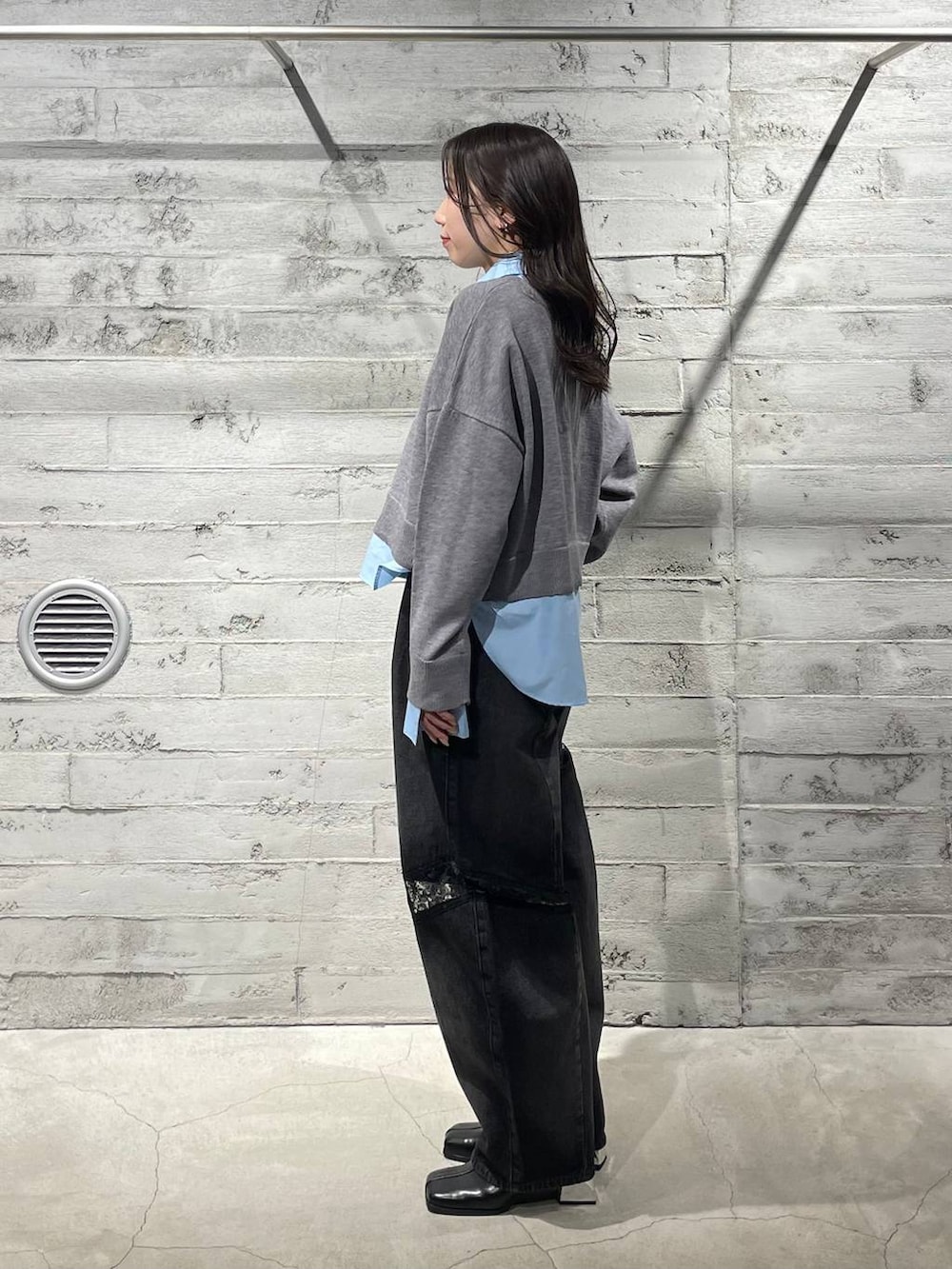 ブラック系のブーツ、ブラック系のデニムパンツ、グレー系のニット/セーターを着用したレディースの冬コーディネートの2枚目の写真