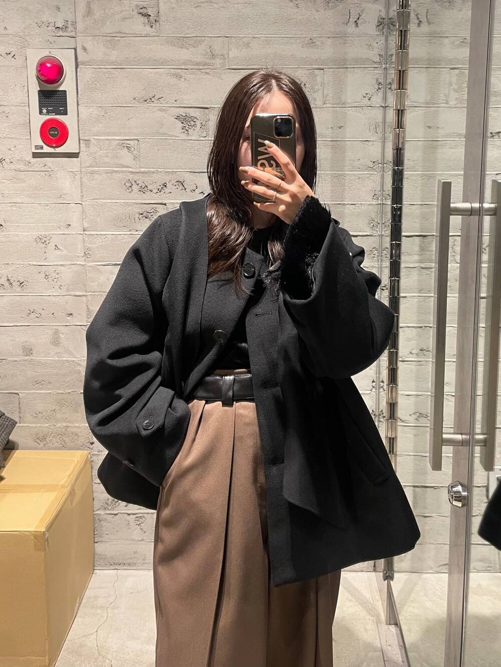 ブラック系のノーカラーコート、ブラウン系のその他パンツ、ブラック系のTシャツ/カットソーを着用したレディースの冬コーディネートの2枚目の写真