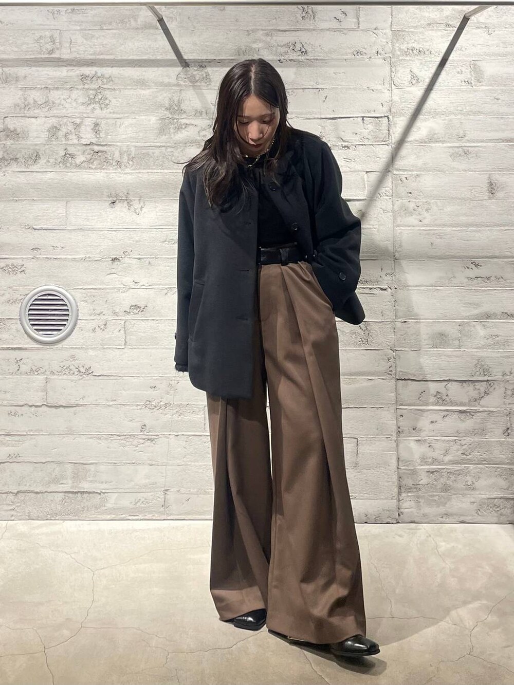ブラック系のブーツ、ブラック系のノーカラーコート、ブラウン系のその他パンツを着用したレディースの冬コーディネートの2枚目の写真