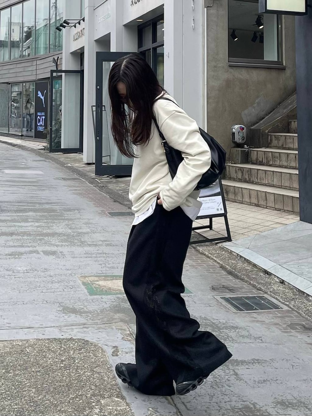 ブラック系のスラックスを着用したレディースの春コーディネートの2枚目の写真