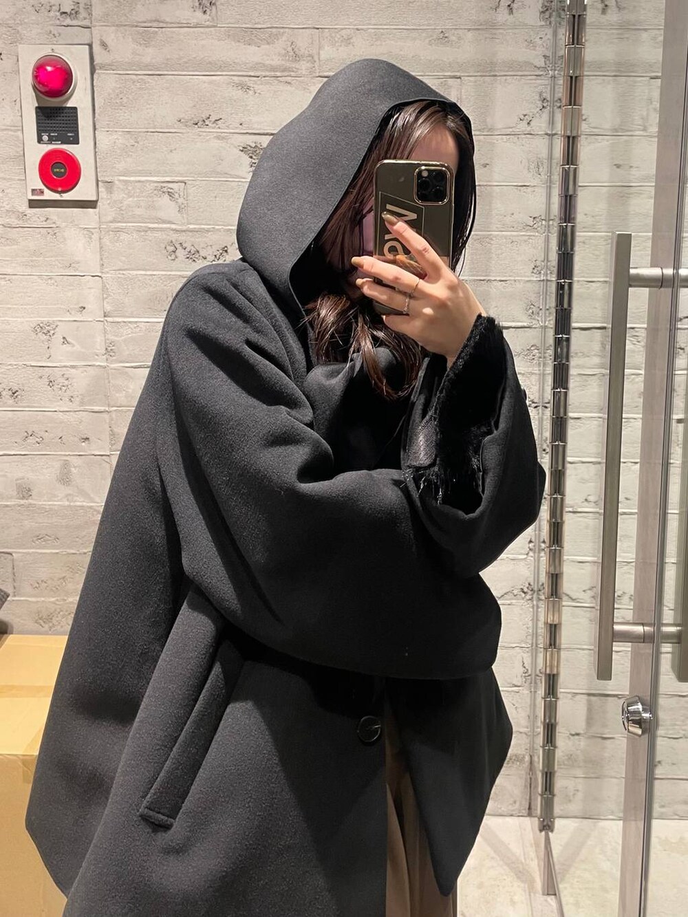 ブラック系のノーカラーコート、ブラウン系のその他パンツ、ブラック系のTシャツ/カットソーを着用したレディースの冬コーディネートの6枚目の写真