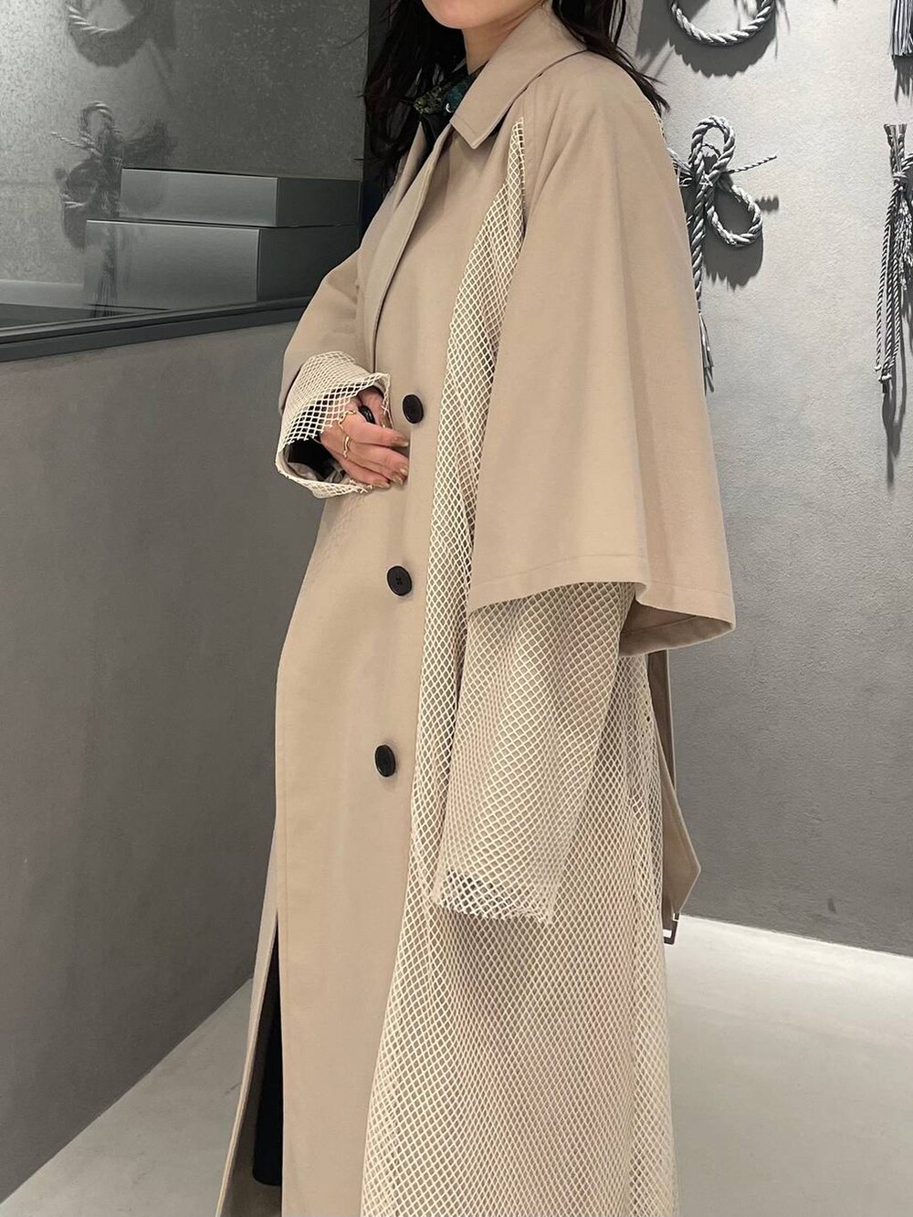 イエロー系のスカート、ブラック系のブーツ、ホワイト系のトレンチコートを着用したレディースの冬コーディネートの6枚目の写真