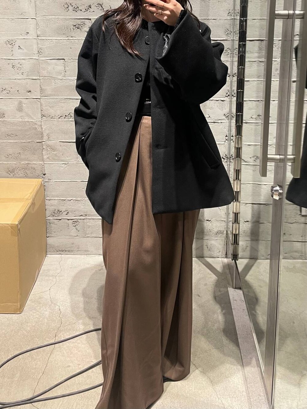 ブラック系のノーカラーコート、ブラウン系のその他パンツ、ブラック系のTシャツ/カットソーを着用したレディースの冬コーディネートの3枚目の写真