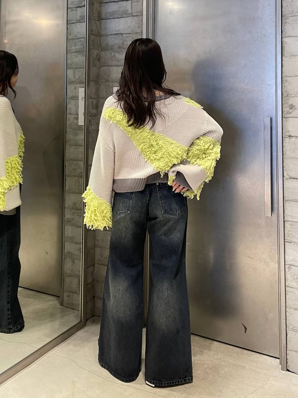 ブルー系のデニムパンツ、ブラック系のブーツ、イエロー系のニット/セーターを着用したレディースの冬コーディネートの3枚目の写真