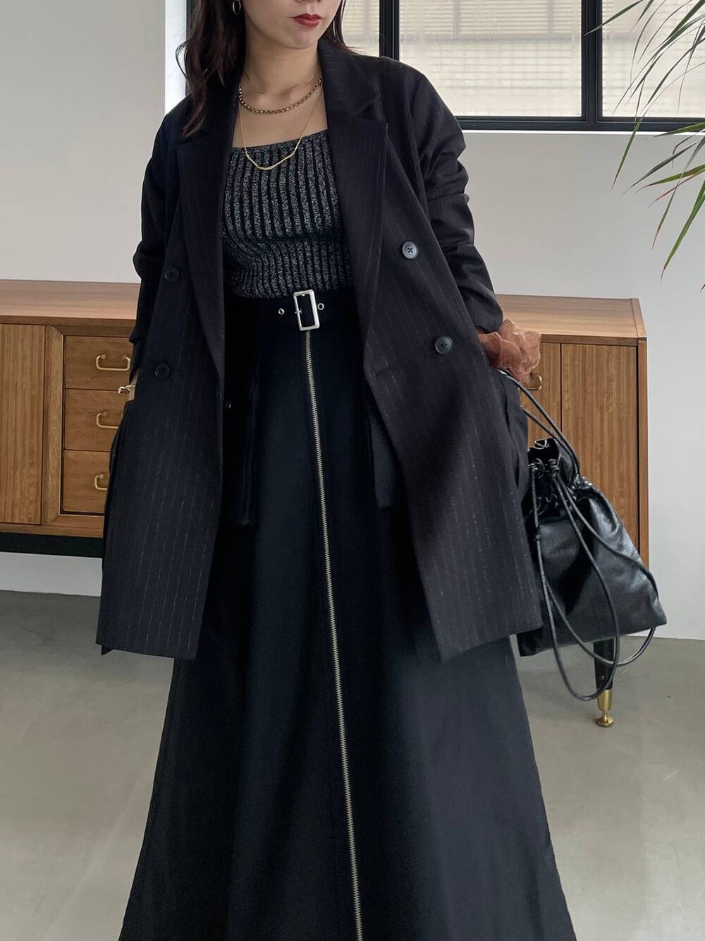 ブラック系のタンクトップ、ブラック系のショルダーバッグ、ブラック系のブーツを着用したレディースの夏コーディネートの6枚目の写真