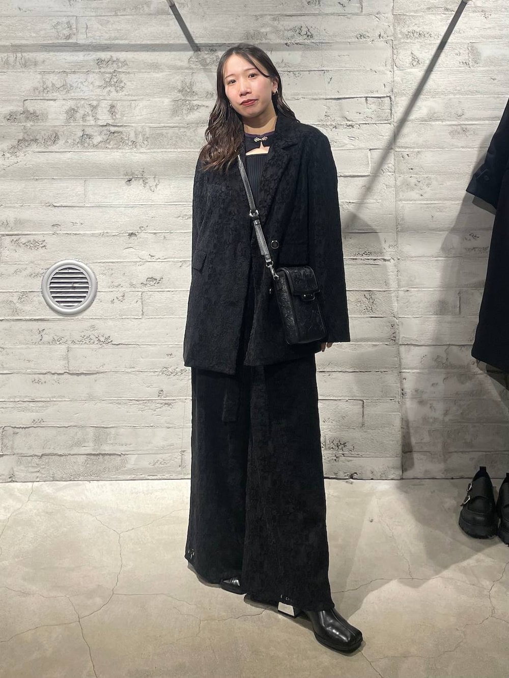 ブラック系のニット/セーター、ブラック系のブーツ、ブラック系のショルダーバッグを着用したレディースの秋コーディネートの4枚目の写真