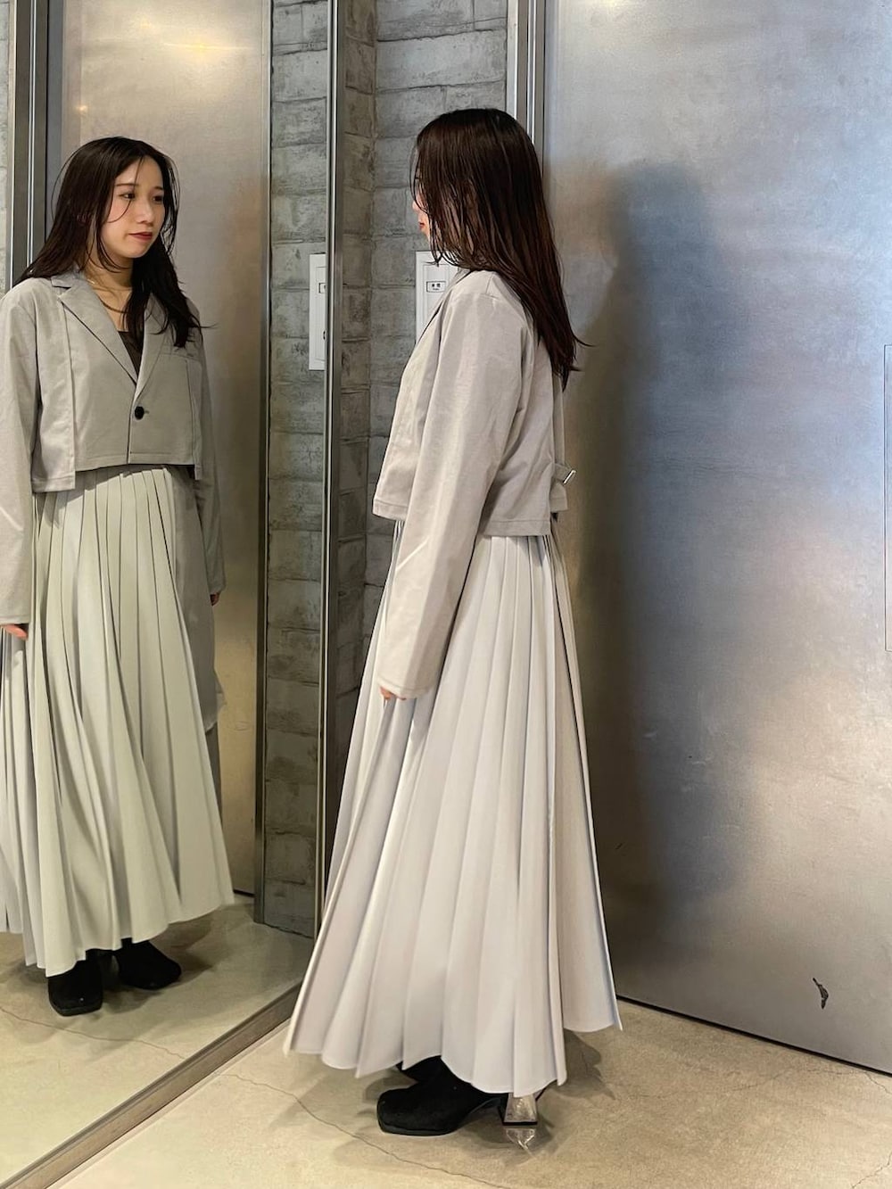 ブラック系のブーツ、グレー系のスカート、グレー系のテーラードジャケットを着用したレディースの春コーディネートの2枚目の写真