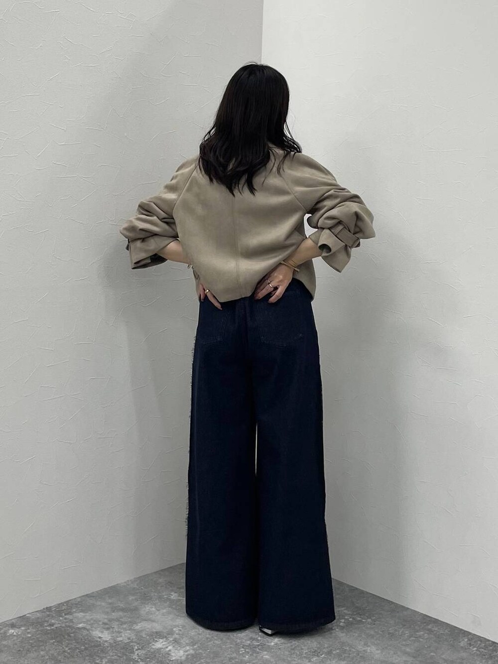 ブルー系のデニムパンツ、ブラック系のブーツ、ベージュ系のトレンチコートを着用したレディースの夏コーディネートの3枚目の写真
