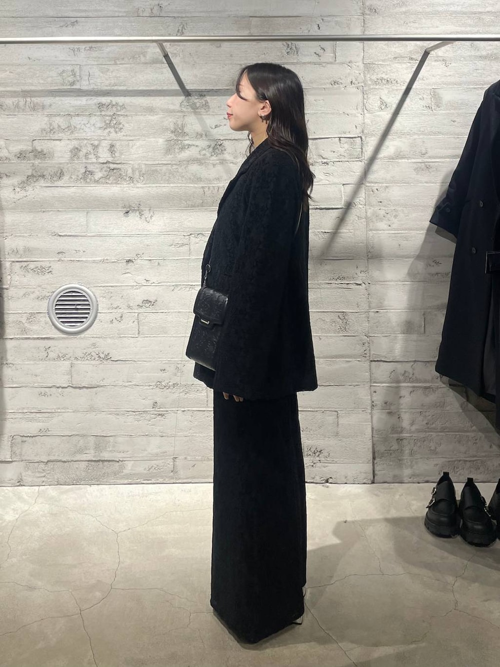 ブラック系のニット/セーター、ブラック系のブーツ、ブラック系のショルダーバッグを着用したレディースの秋コーディネートの2枚目の写真
