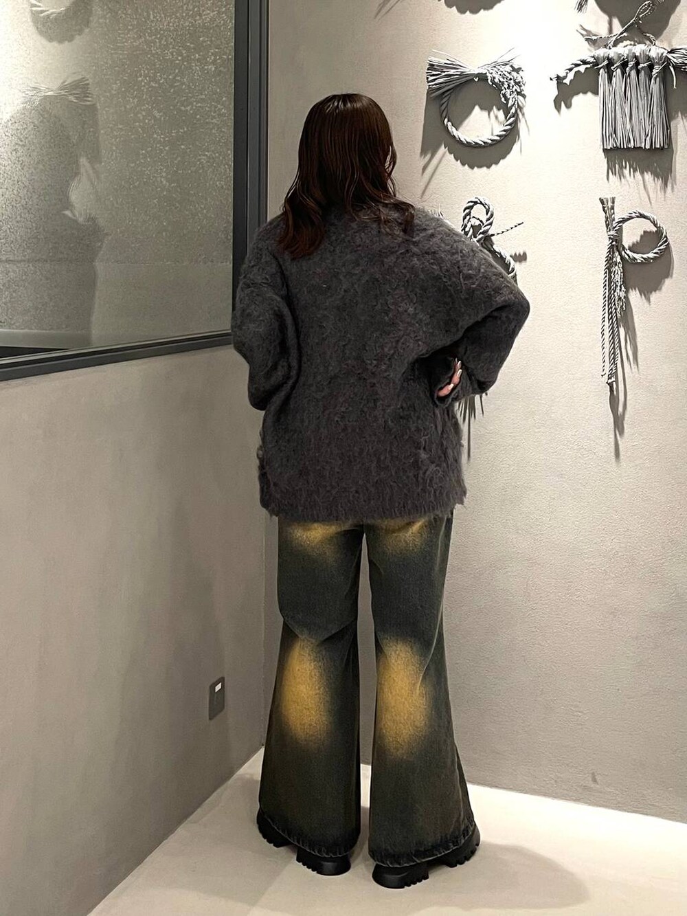 オレンジ系のデニムパンツ、ブラック系のブーツ、グレー系のカーディガン/ボレロを着用したレディースの秋コーディネートの3枚目の写真