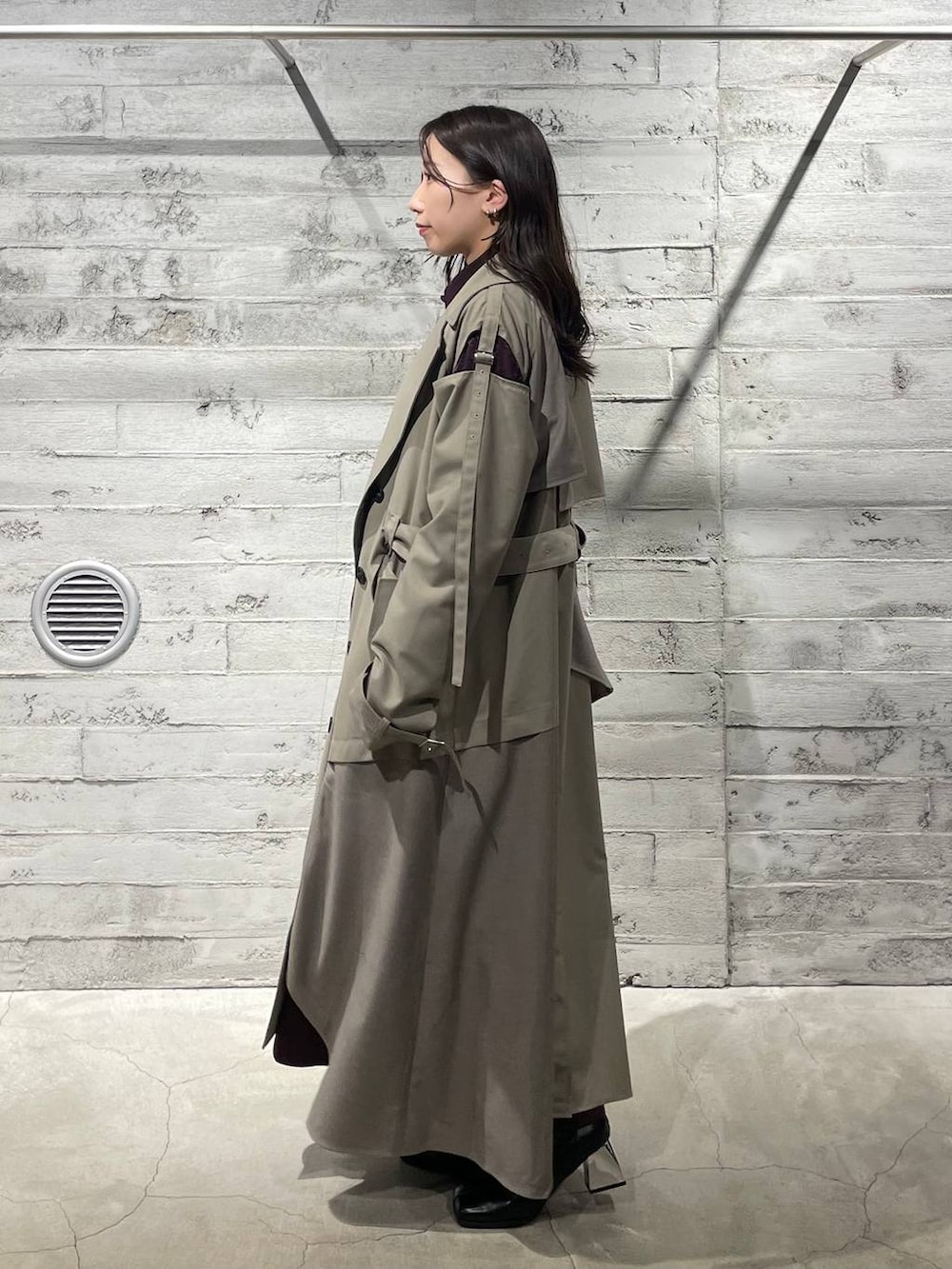 ブラック系のブーツ、レッド系のワンピース、ベージュ系のトレンチコートを着用したレディースの冬コーディネートの2枚目の写真