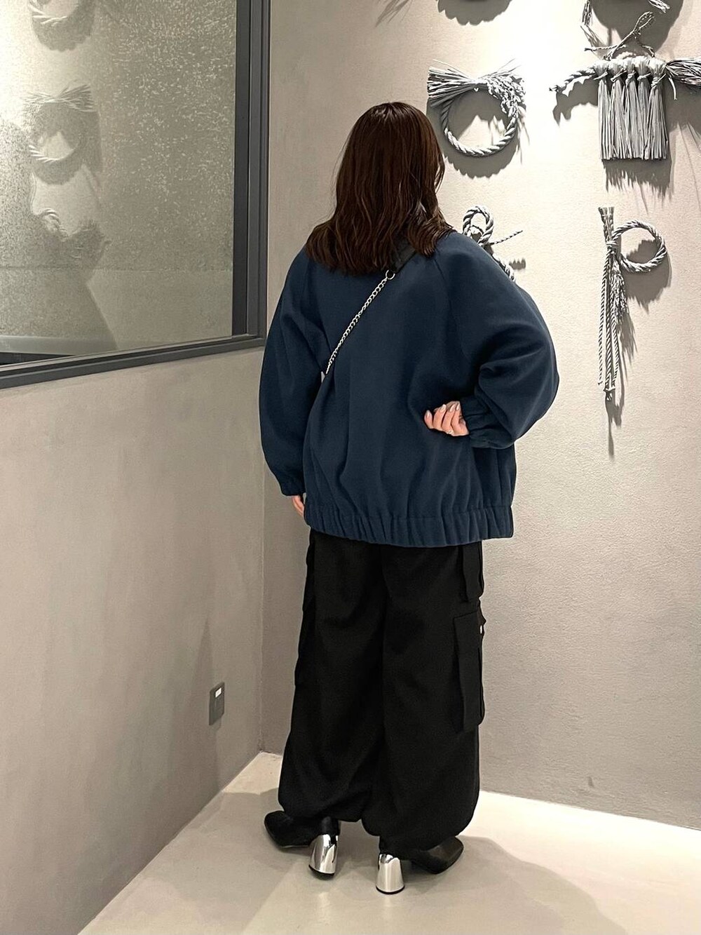 ブルー系のブルゾン、ブラック系のショルダーバッグ、ブラック系のブーツを着用したレディースの秋コーディネートの3枚目の写真