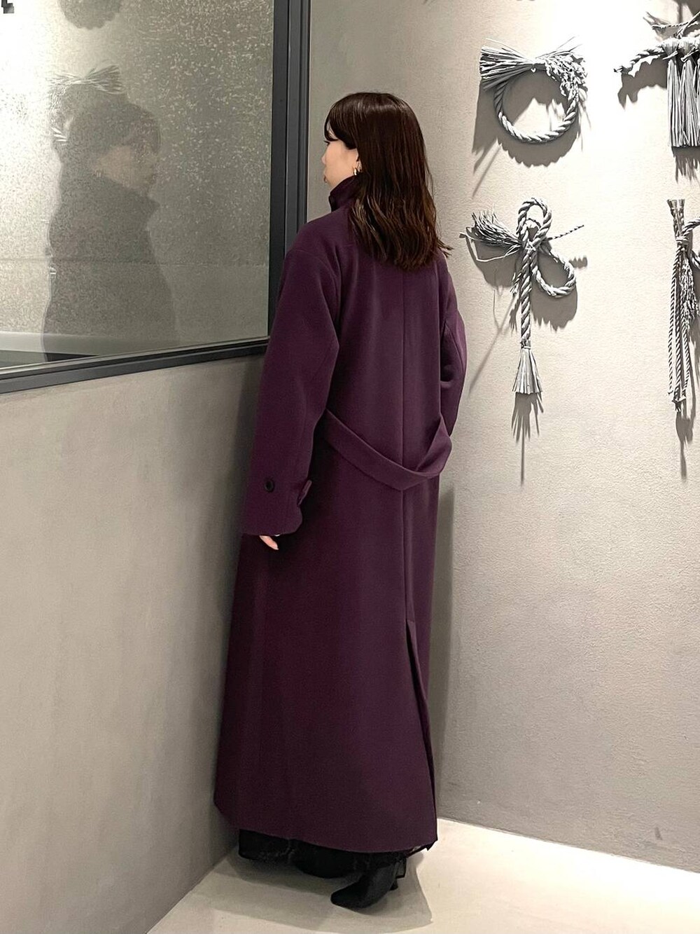 パープル系のチェスターコート、ブラック系のブーツ、レッド系のニット/セーターを着用したレディースの秋コーディネートの2枚目の写真