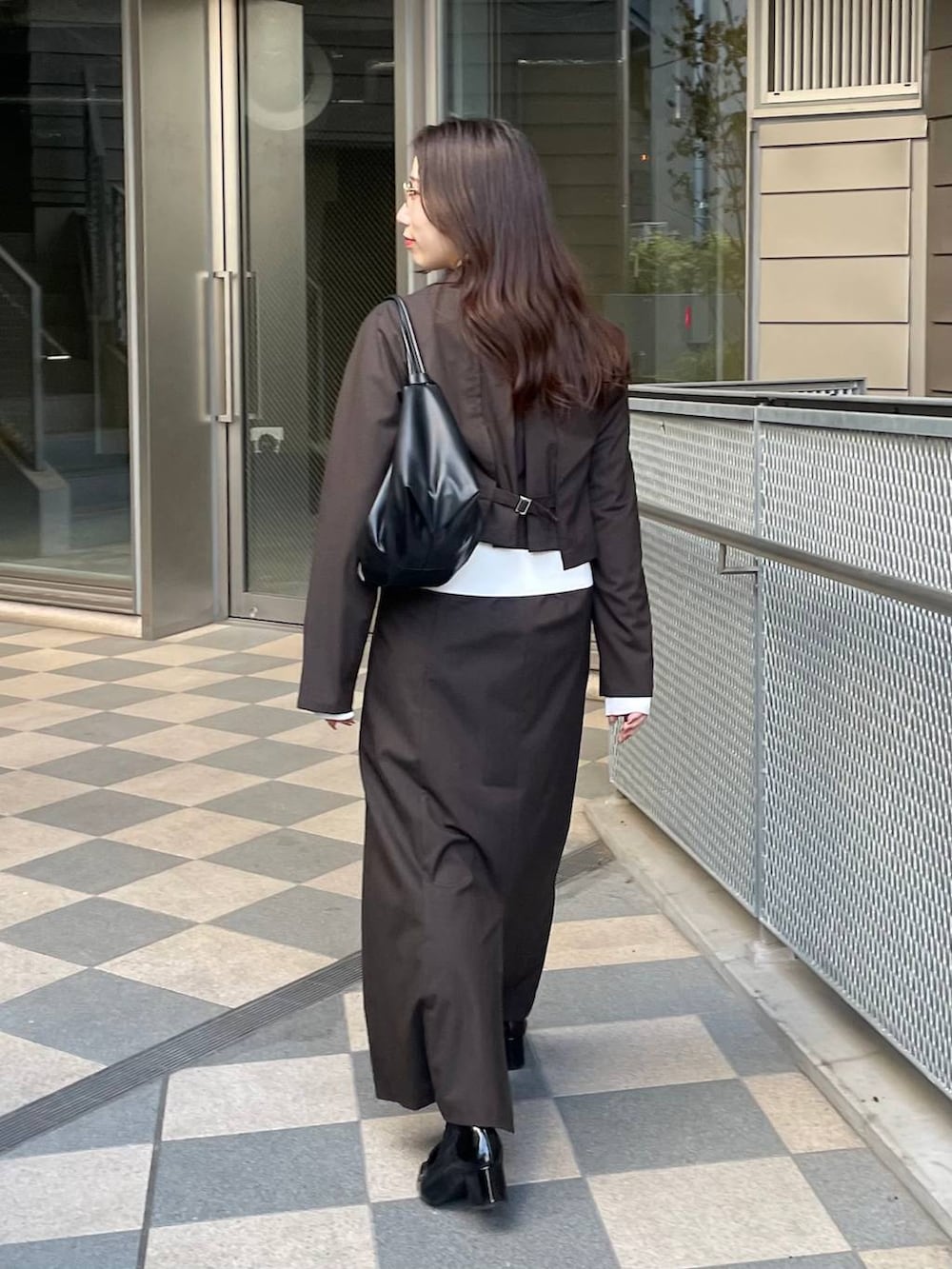 ブラック系のショルダーバッグ、ブラウン系のテーラードジャケット、ブラウン系のスカートを着用したレディースの冬コーディネートの3枚目の写真