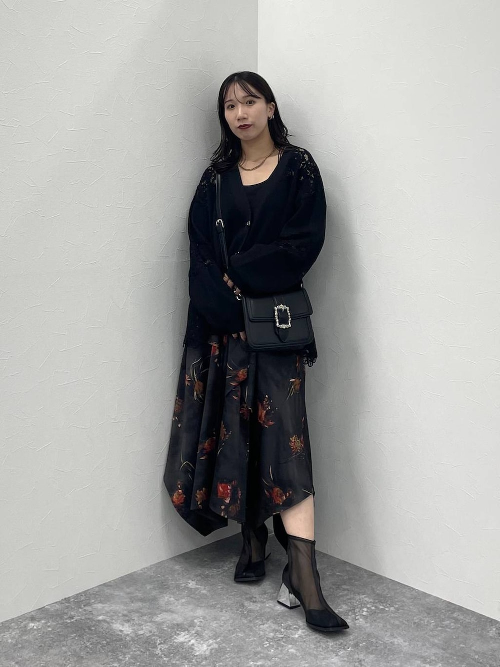 ブラック系のショルダーバッグ、ブラック系のカーディガン/ボレロ、ブラック系のブーツを着用したレディースの秋コーディネートの2枚目の写真