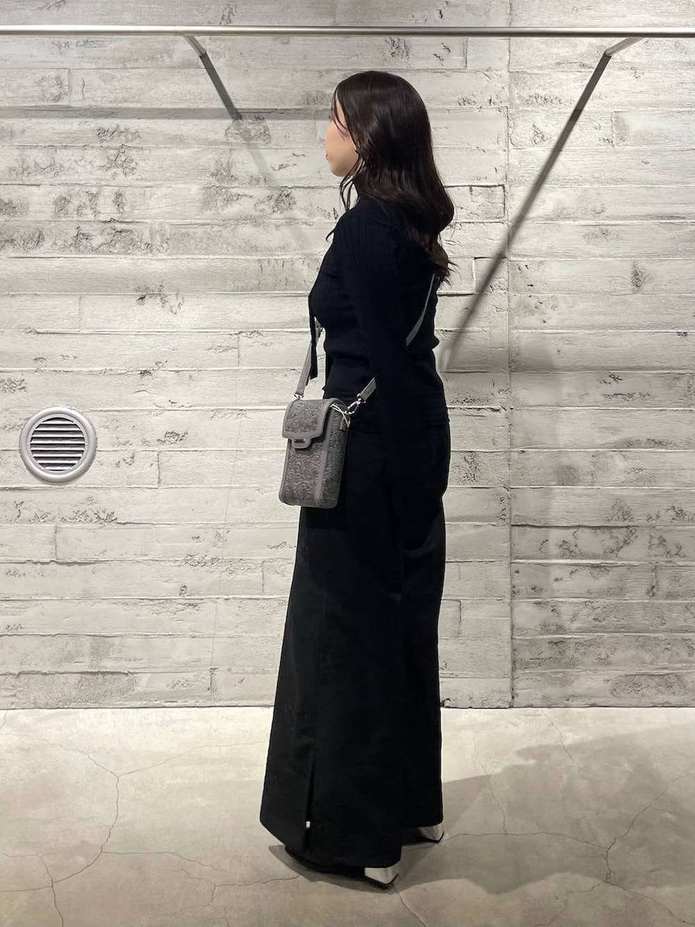 ブラック系のブーツ、グレー系のショルダーバッグ、ブラック系のニット/セーターを着用したレディースの冬コーディネートの2枚目の写真