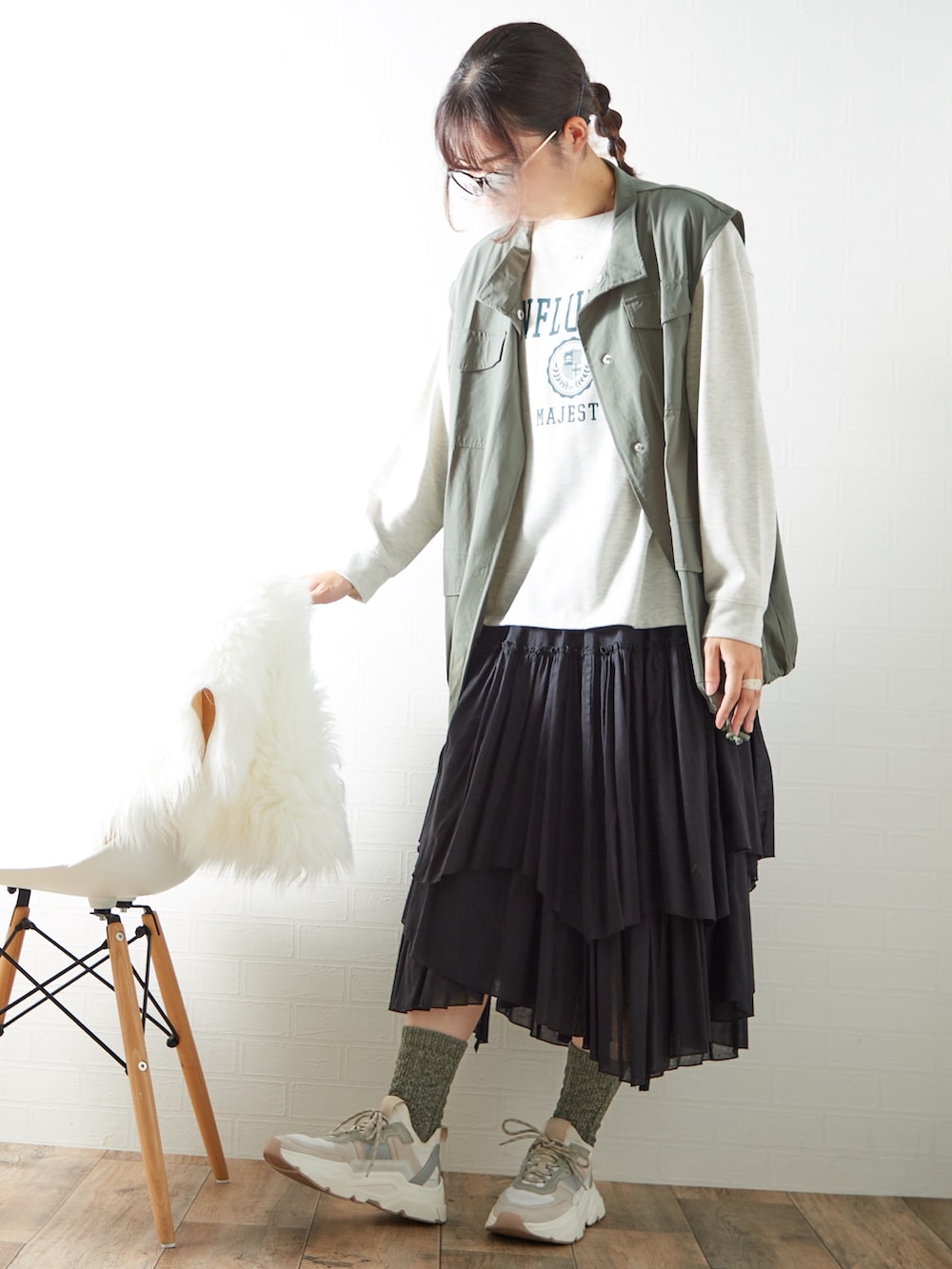 ブラック系のスカート、ベージュ系のTシャツ/カットソー、グリーン系のベストを着用したレディースの秋コーディネートの2枚目の写真