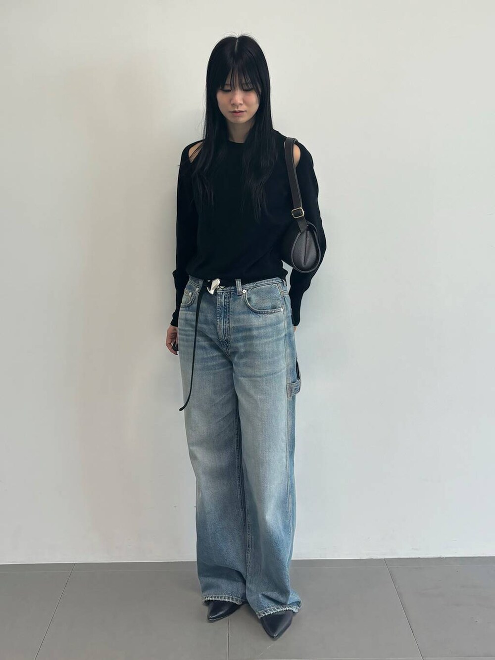 ブルー系のデニムパンツ、ブラック系のニット/セーター、ブラック系のベルトを着用したレディースの冬コーディネートの4枚目の写真