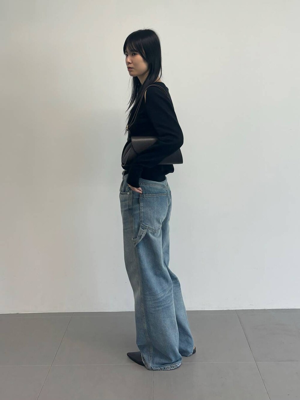 ブルー系のデニムパンツ、ブラック系のニット/セーター、ブラック系のベルトを着用したレディースの冬コーディネートの2枚目の写真