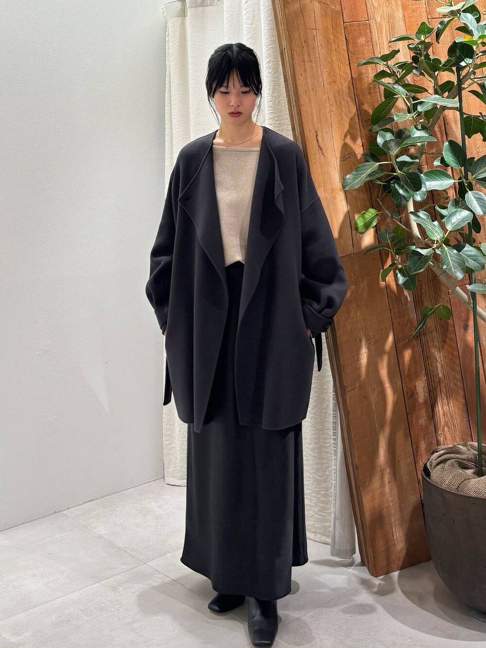 グレー系のニット/セーター、グレー系のピーコート、ブラック系のスカートを着用したレディースの秋コーディネートの2枚目の写真