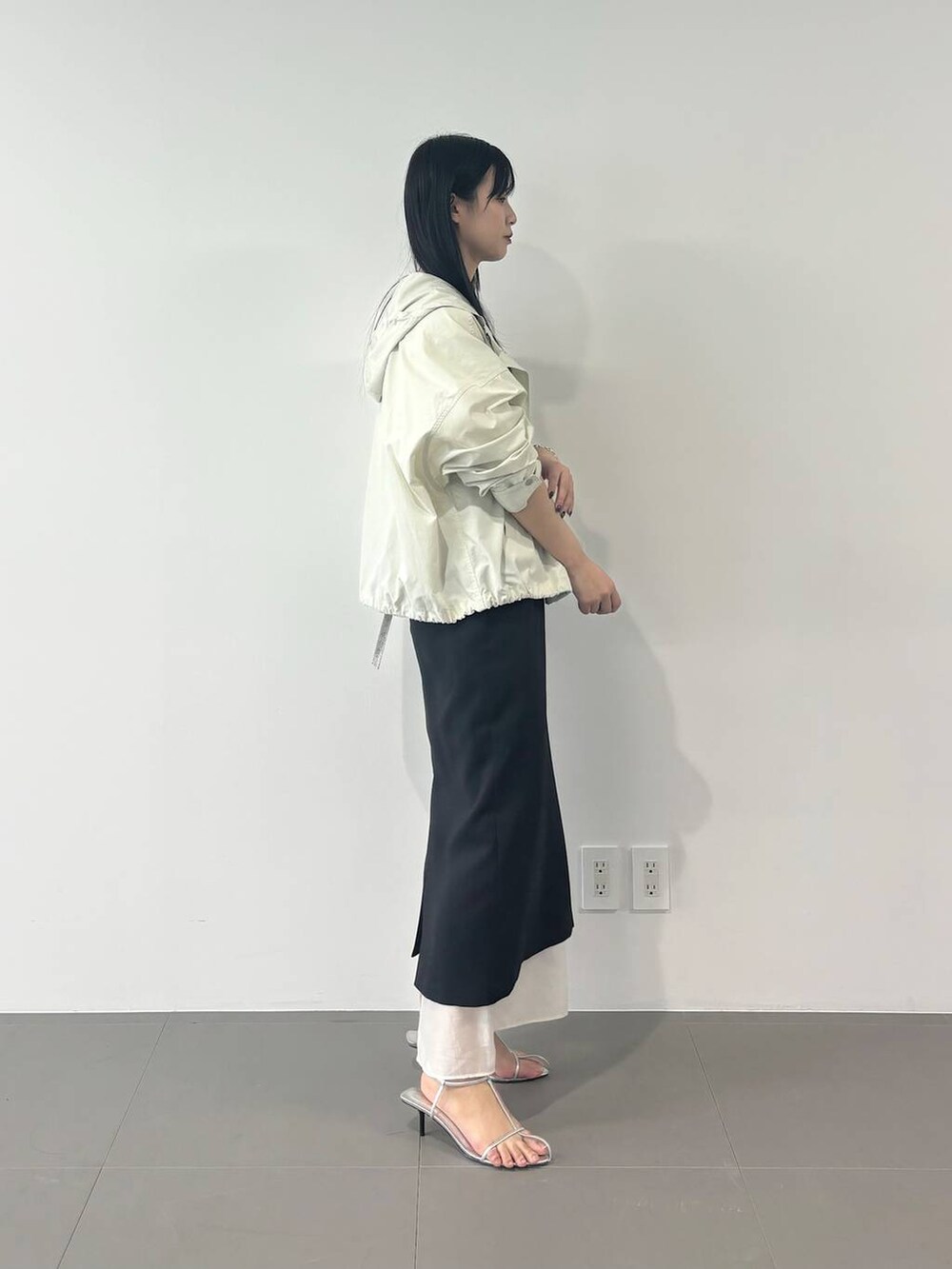 ホワイト系のマウンテンパーカー、ブラック系のスカート、ホワイト系のTシャツ/カットソーを着用したレディースの春コーディネートの2枚目の写真