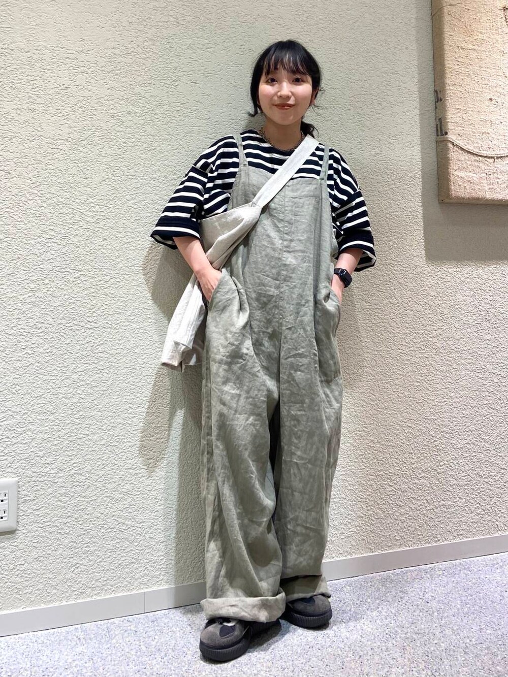 ベージュ系のサロペット/オーバーオール、ベージュ系のトートバッグ、ブラック系のTシャツ/カットソーを着用したレディースの春コーディネートの5枚目の写真