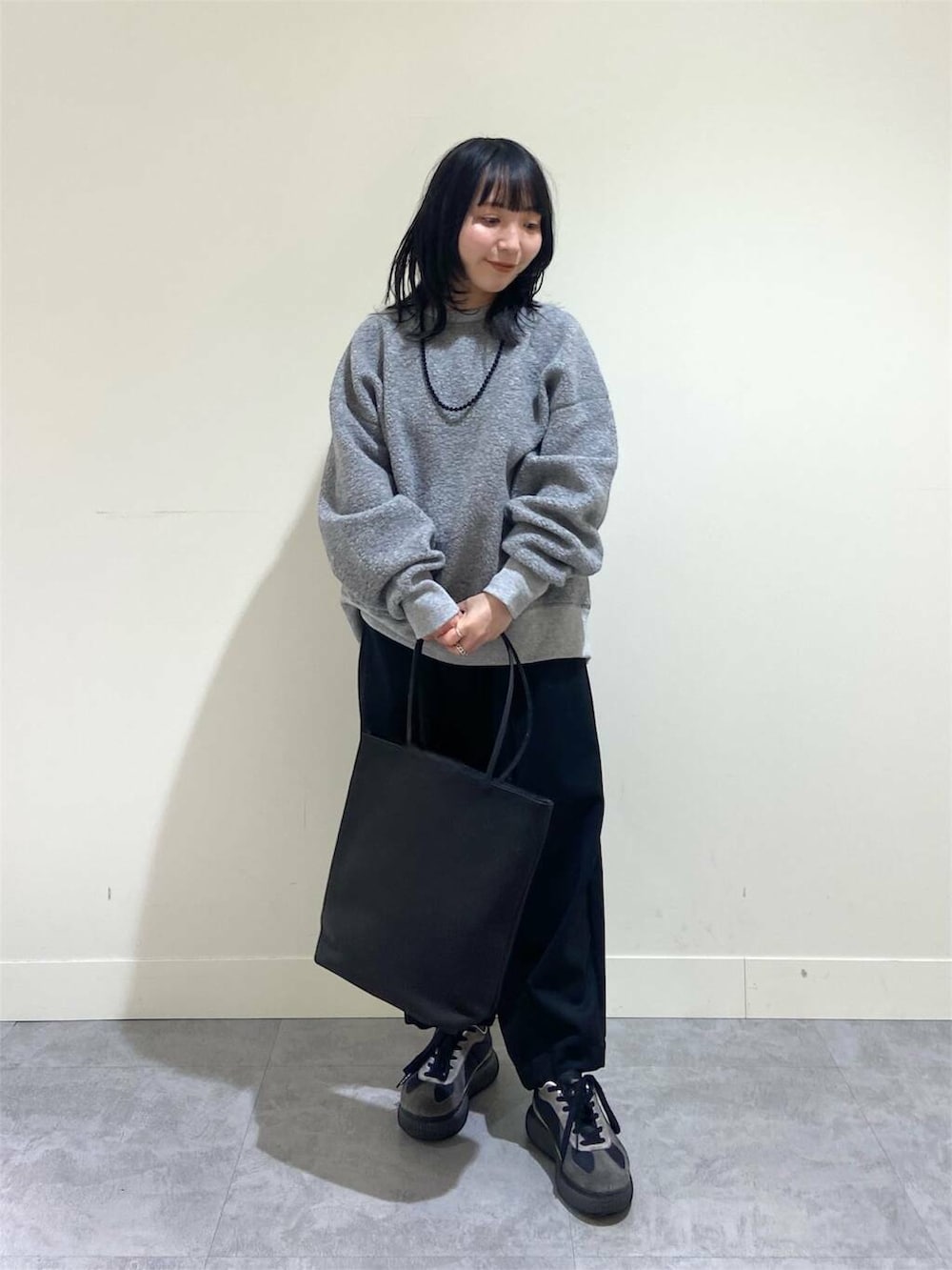 グレー系のTシャツ/カットソー、ブラック系のその他パンツ、ブラック系のトートバッグを着用したレディースの冬コーディネートの2枚目の写真