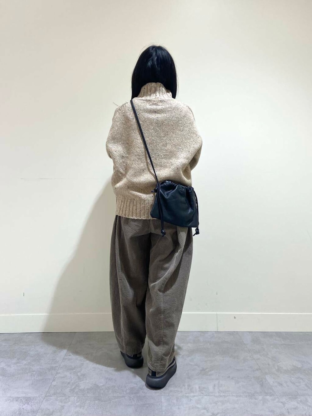 ベージュ系のニット/セーター、グレー系のその他パンツ、ブラック系のショルダーバッグを着用したレディースの冬コーディネートの4枚目の写真