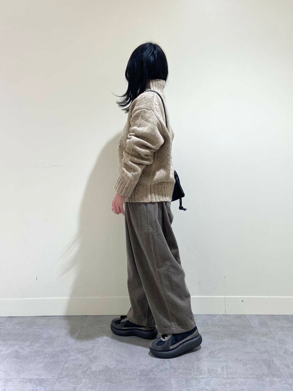 ベージュ系のニット/セーター、グレー系のその他パンツ、ブラック系のショルダーバッグを着用したレディースの冬コーディネートの3枚目の写真