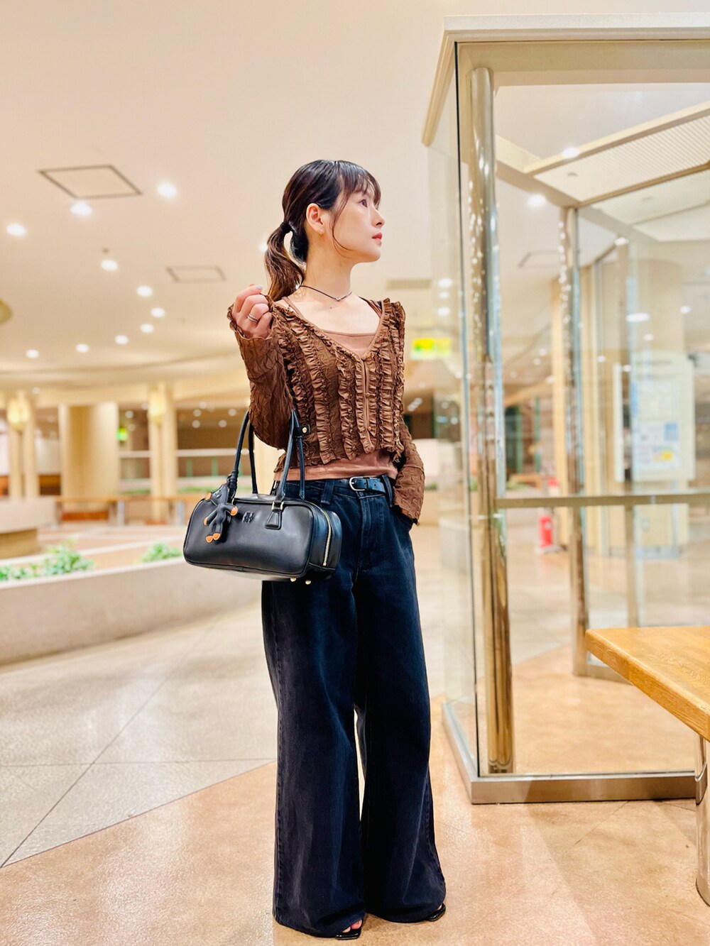 ブラック系のデニムパンツ、ブラック系のボストンバッグ、ブラウン系のキャミソールを着用したレディースの夏コーディネートの2枚目の写真