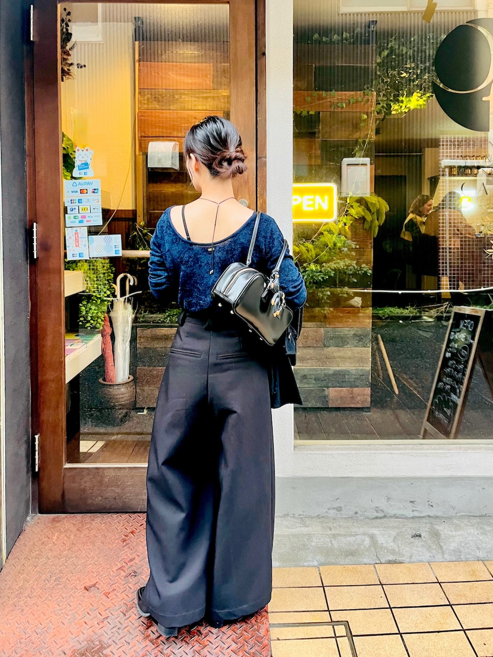 ブラック系のスラックス、ブルー系のニット/セーター、ブラック系のボストンバッグを着用したレディースの秋コーディネートの2枚目の写真