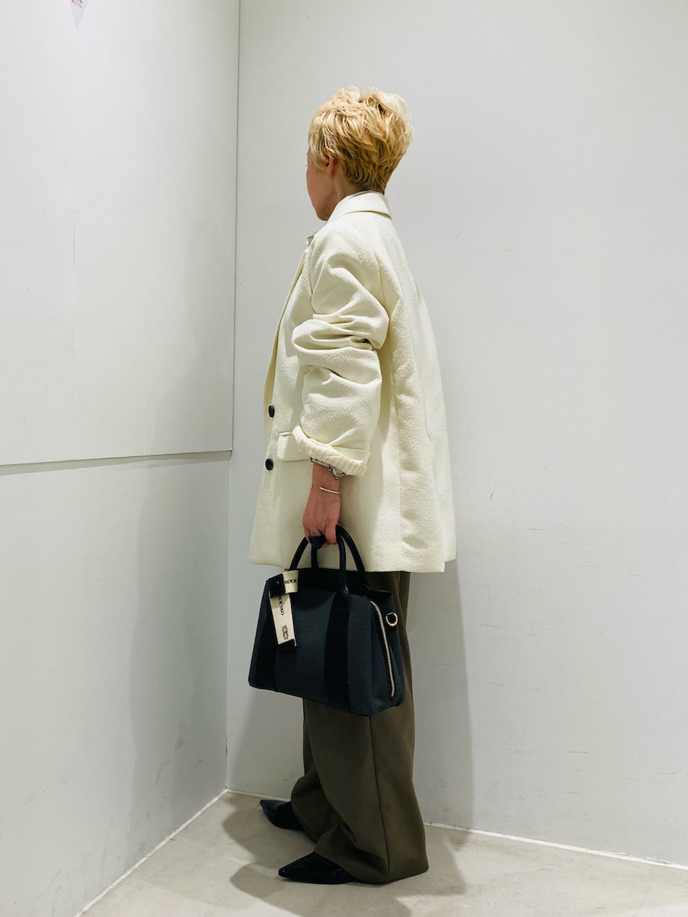 ホワイト系のテーラードジャケット、ホワイト系のシャツ/ブラウス、グリーン系のスラックスを着用したレディースの冬コーディネートの2枚目の写真