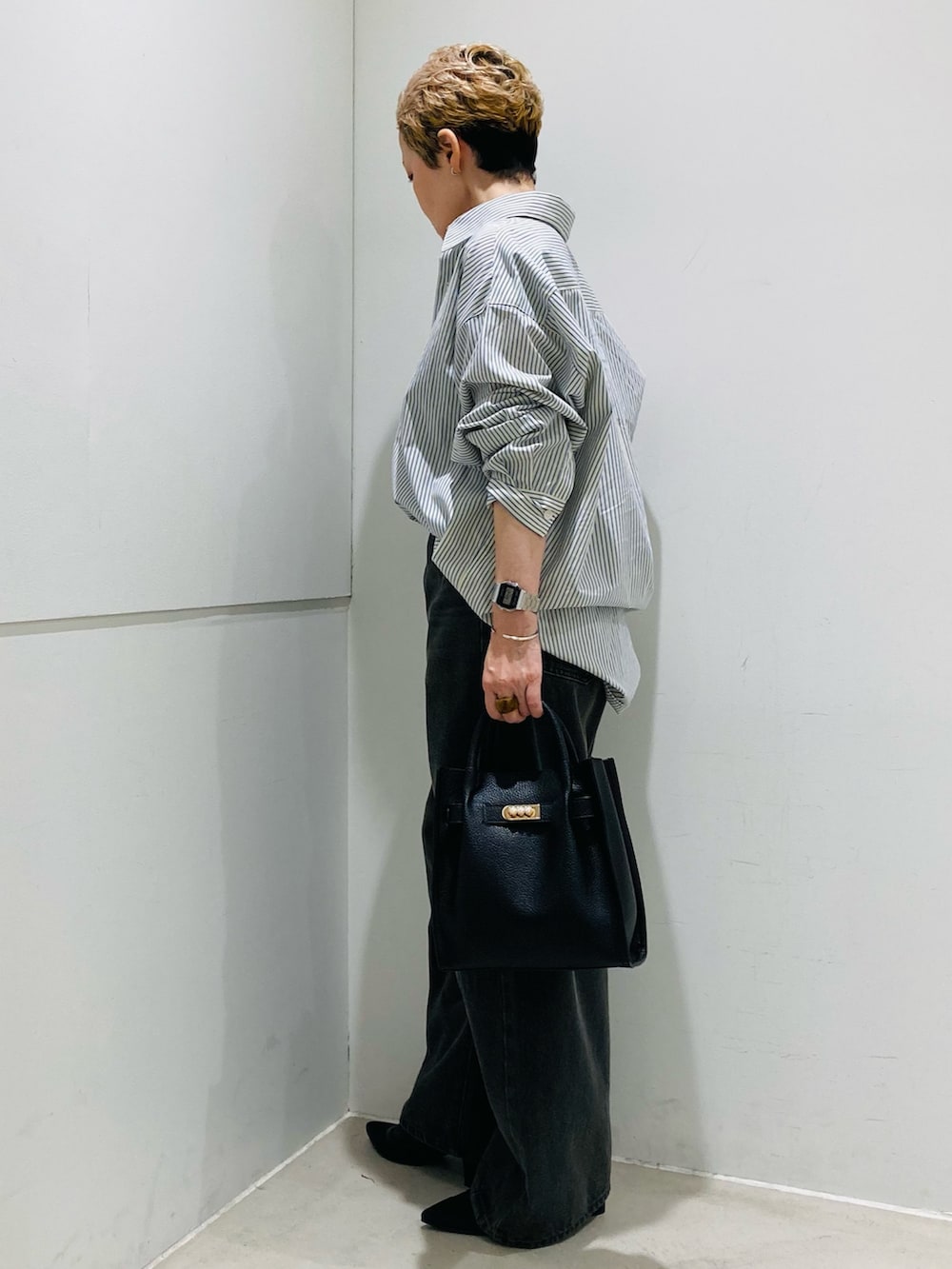 ホワイト系のシャツ/ブラウス、ブラック系のハンドバッグ、グレー系のデニムパンツを着用したレディースの秋コーディネートの2枚目の写真