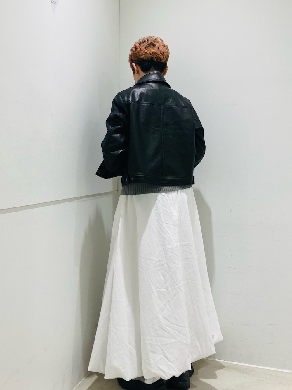 ブラック系のその他アウター、グレー系のニット/セーター、ホワイト系のスカートを着用したレディースの秋コーディネートの3枚目の写真