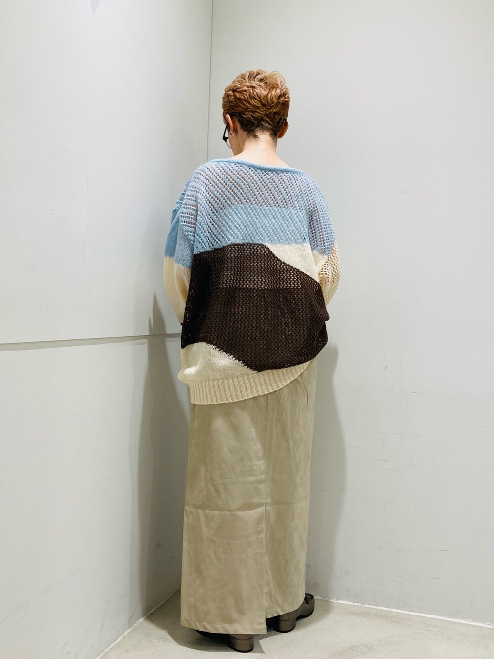 ブルー系のニット/セーター、ホワイト系のキャミソール、ベージュ系のスカートを着用したレディースの秋コーディネートの3枚目の写真