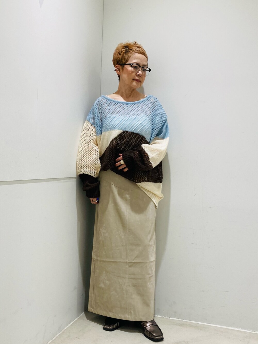 ブルー系のニット/セーター、ホワイト系のキャミソール、ベージュ系のスカートを着用したレディースの秋コーディネートの4枚目の写真