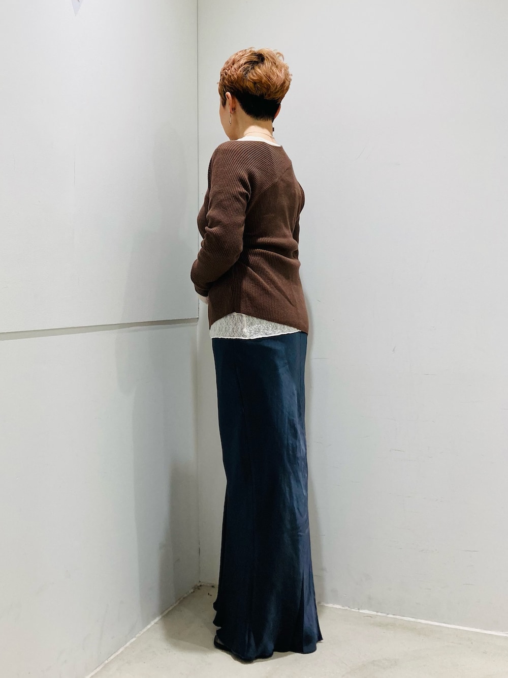 ブラウン系のニット/セーター、ホワイト系のTシャツ/カットソー、グレー系のスカートを着用したレディースの秋コーディネートの2枚目の写真