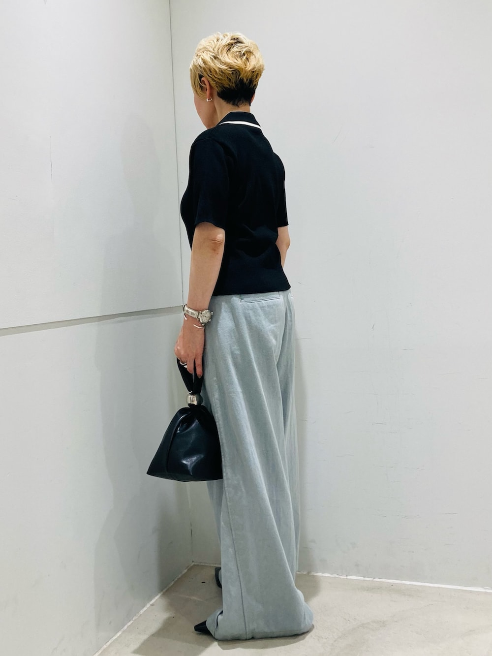 ブラック系のニット/セーター、ブラック系のパンプス、ブルー系のデニムパンツを着用したレディースの春コーディネートの2枚目の写真