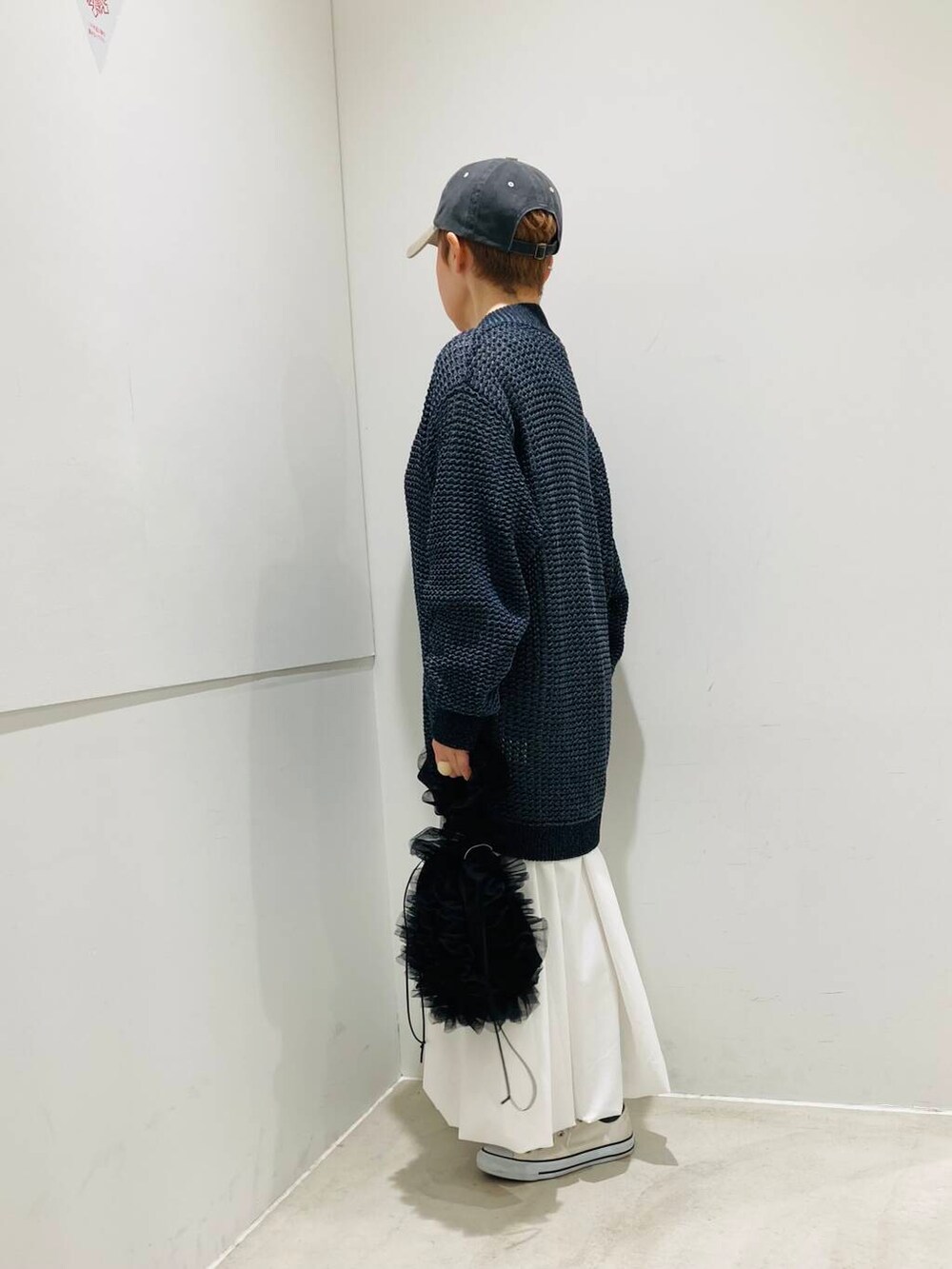ホワイト系のスカート、ホワイト系のニット/セーター、ブラック系のハンドバッグを着用したレディースの春コーディネートの2枚目の写真