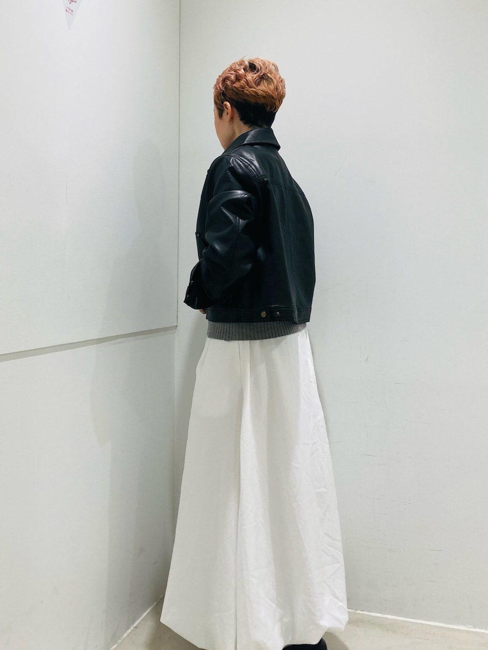 ブラック系のその他アウター、グレー系のニット/セーター、ホワイト系のスカートを着用したレディースの秋コーディネートの2枚目の写真