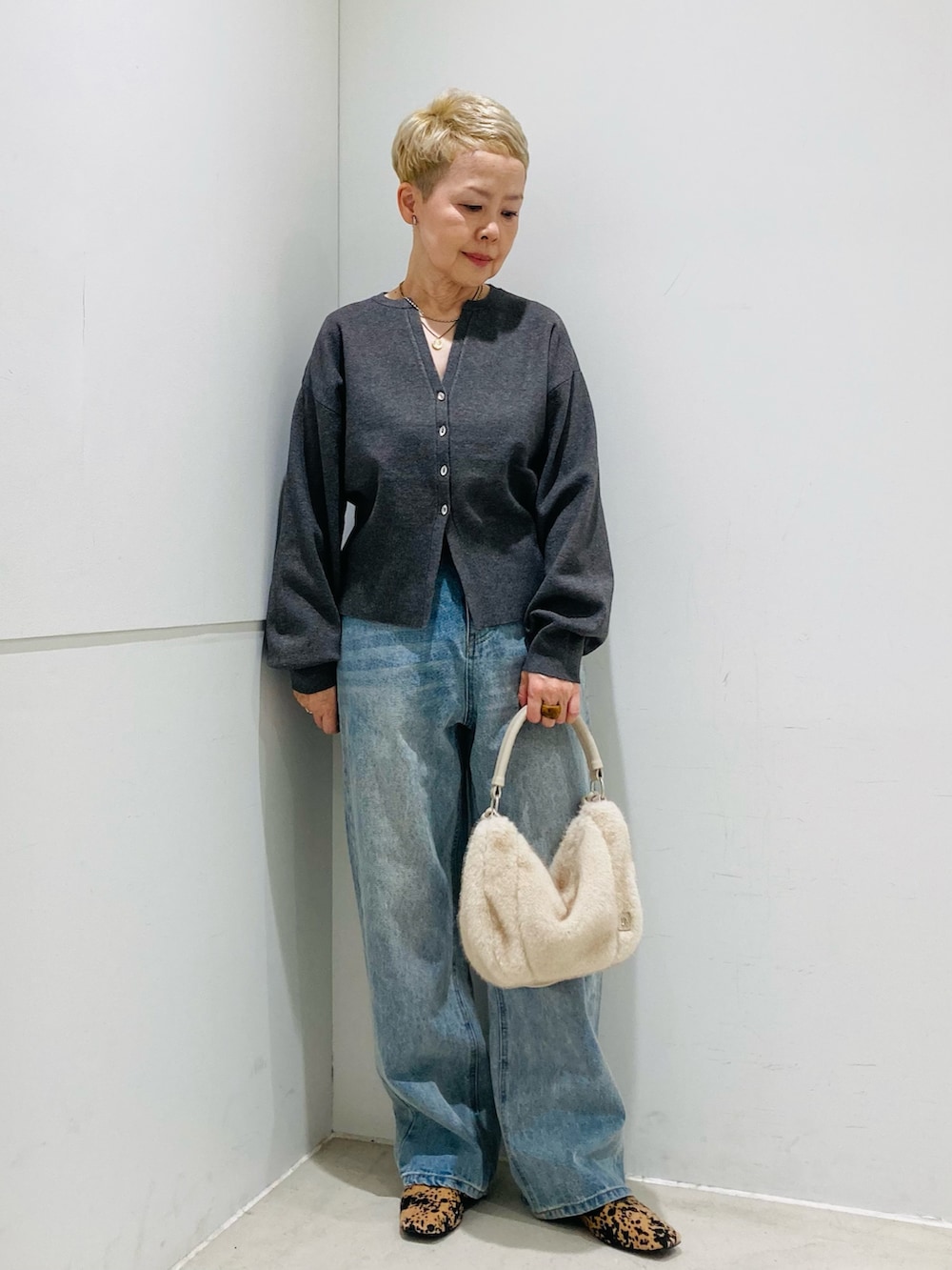 グレー系のカーディガン/ボレロ、ホワイト系のショルダーバッグ、ブルー系のデニムパンツを着用したレディースの秋コーディネートの2枚目の写真