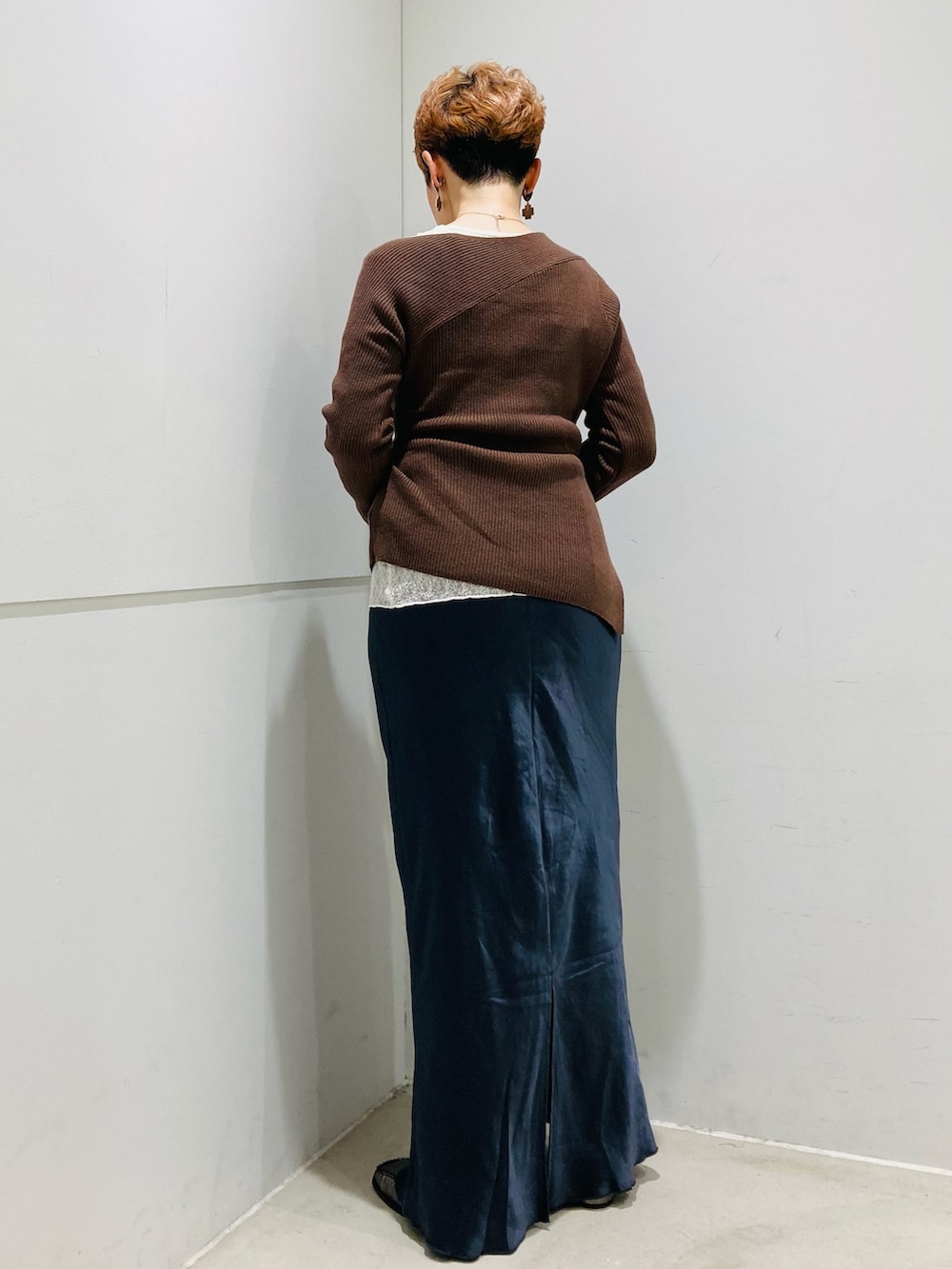 ブラウン系のニット/セーター、ホワイト系のTシャツ/カットソー、グレー系のスカートを着用したレディースの秋コーディネートの3枚目の写真