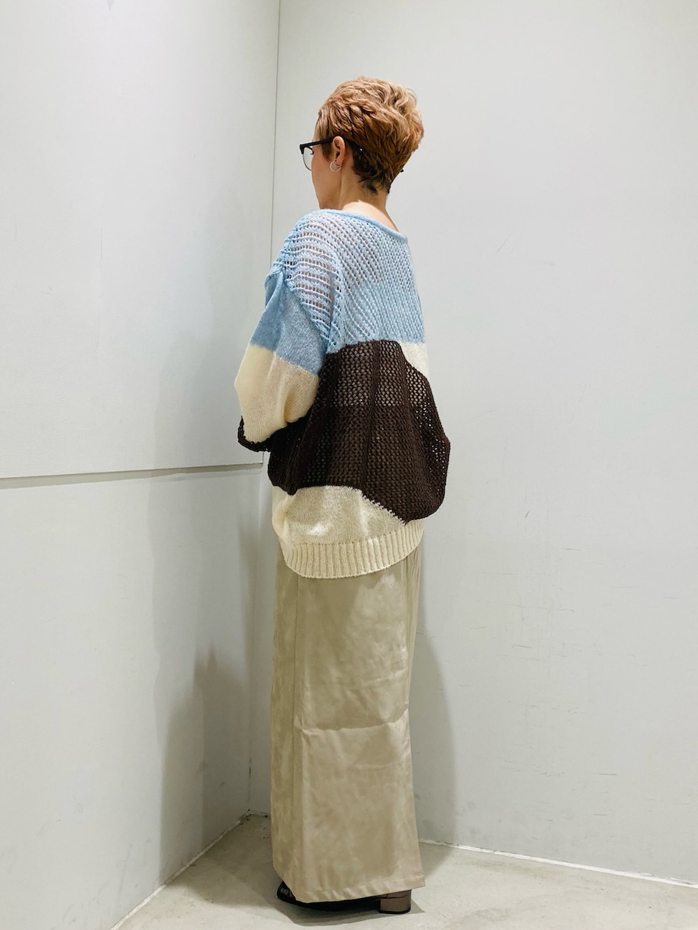 ブルー系のニット/セーター、ホワイト系のキャミソール、ベージュ系のスカートを着用したレディースの秋コーディネートの2枚目の写真