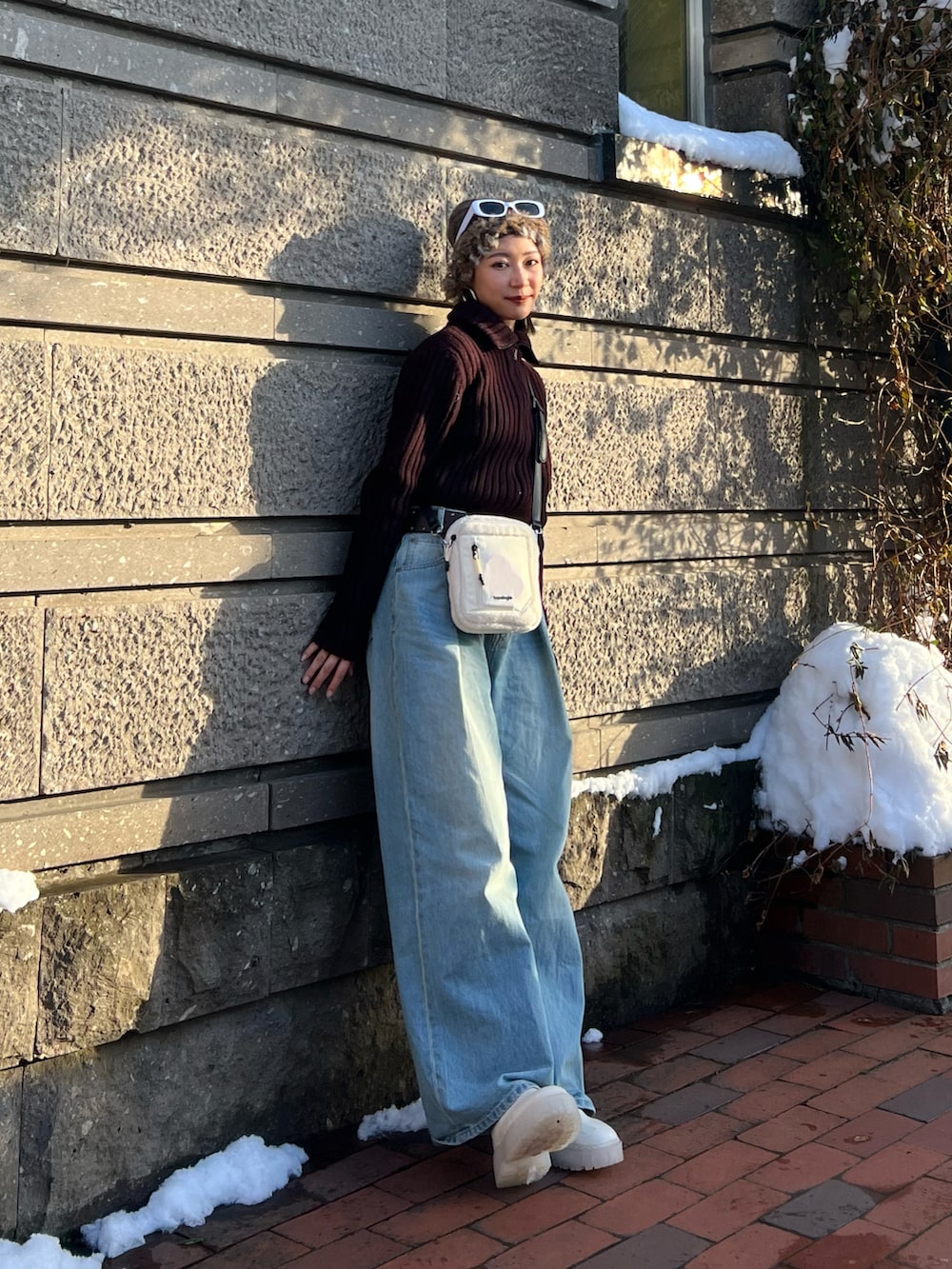 ブルー系のデニムパンツ、ホワイト系のブーツ、ホワイト系のショルダーバッグを着用したレディースの冬コーディネートの2枚目の写真